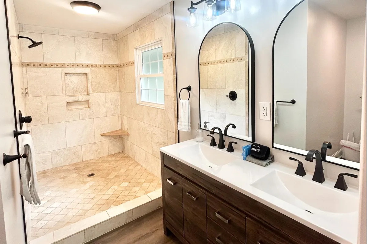 A spa-inspired bathroom featuring a large shower area, double vanity sinks, and elegant arched mirrors. Subtle lighting and refined finishes create a tranquil, upscale atmosphere.
