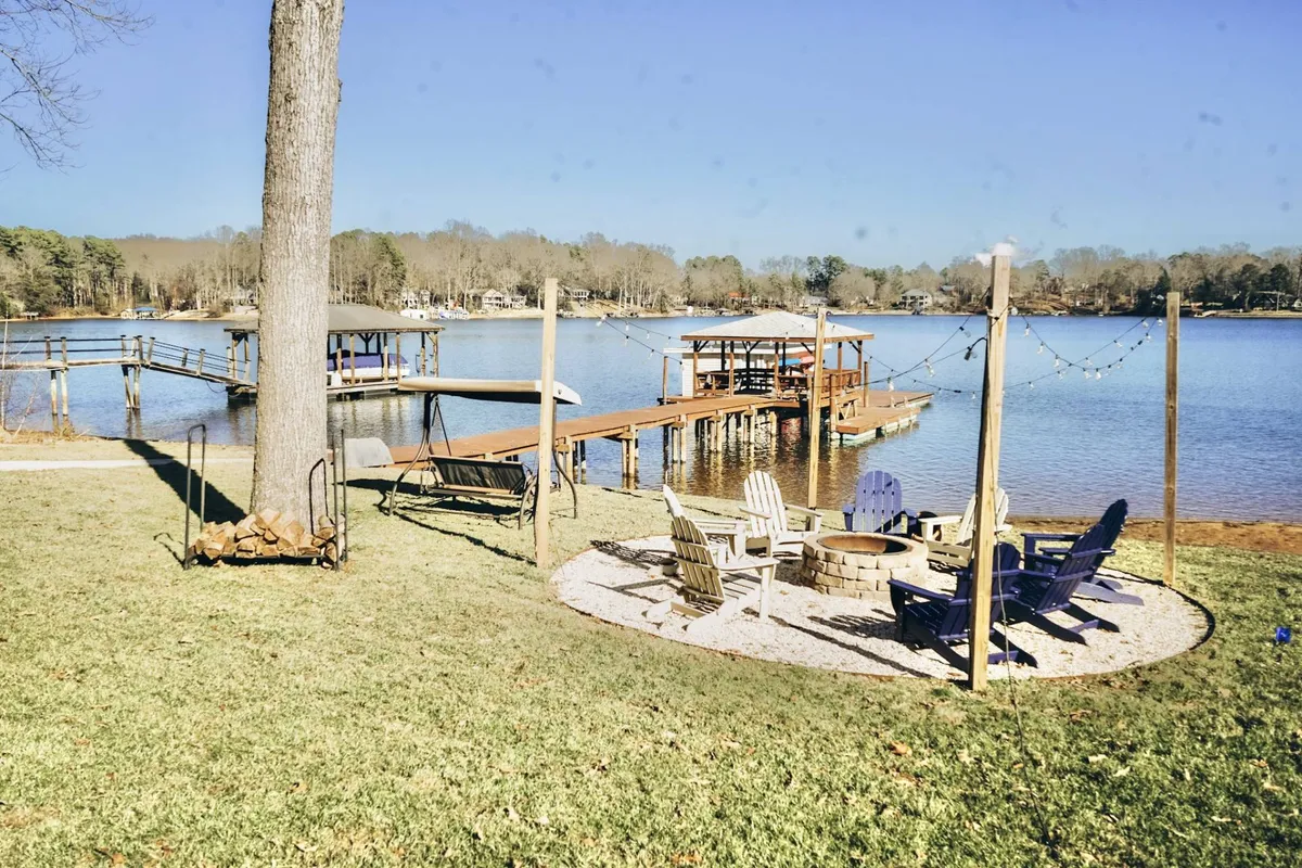 A scenic lakeside spot with a dock, fire pit, and Adirondack chairs arranged for gathering. The tranquil water and surrounding natural beauty set the stage for evening fires, storytelling, and witnessing unforgettable sunsets.
