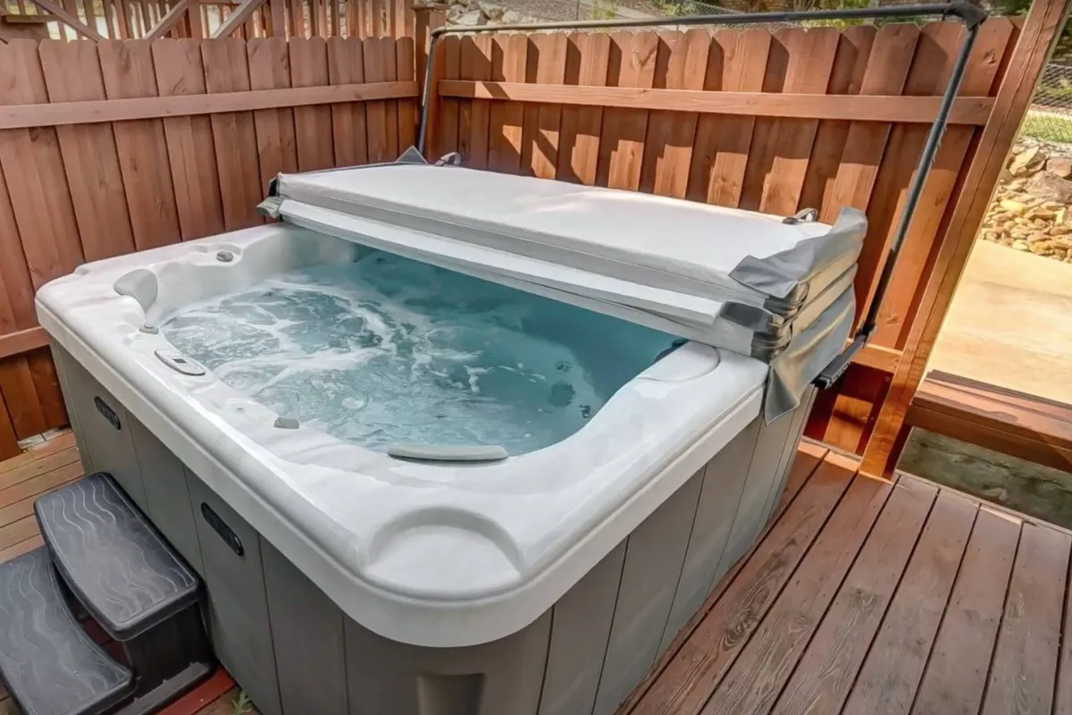 A tranquil outdoor hot tub surrounded by a wooden fence, with easy-to-access steps, inviting guests to relax. The setting hints at a peaceful evening under the stars, ideal for unwinding after a day of adventure.